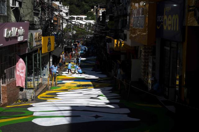 Local artists paint a street ahead of the FIFA World Cup 2026 in the Rocinha favela in Rio de Janeiro, Brazil, on May 5, 2026. (Photo by Pablo PORCIUNCULA / AFP)