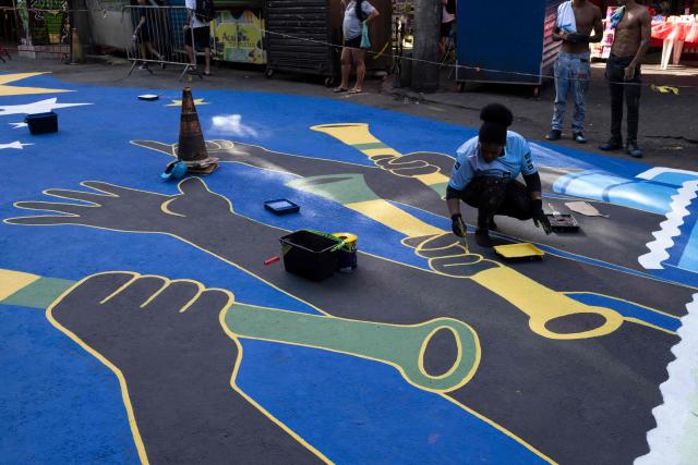 A local artist paints a street ahead of the FIFA World Cup 2026 in the Rocinha favela in Rio de Janeiro, Brazil, on May 5, 2026. (Photo by Pablo PORCIUNCULA / AFP)