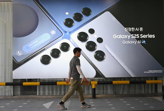 (FILES) A man walks past an advertisement for the Samsung Galaxy S25 series smartphones at a Samsung store in Seoul on July 8, 2025. The market value of Samsung Electronics topped $1 trillion for the first time on May 6, 2026, riding an AI chip boom that has sent South Korean stocks to record highs. (Photo by Jung Yeon-je / AFP)