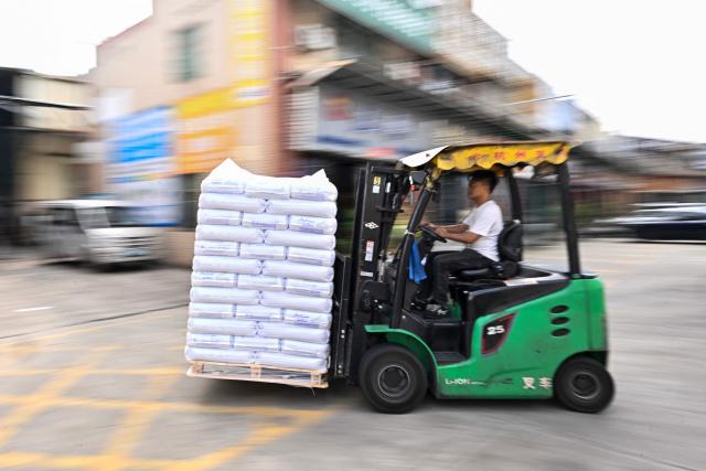 This picture taken on April 29, 2026 shows an employee driving a forklift as he unloads bales from a truck at the Zhangmutou Plastic Raw Material Market in Dongguan, in southern China's Guangdong province. Vacuum cleaners and vapes could get more expensive if the Iran war drags on for much longer, Chinese factory owners and traders warn, as the world's manufacturing hub reels from "crazy" costs. (Photo by Pedro PARDO / AFP) / To go with 'CHINA-IRAN-MANUFACTURING-TRADE-PLASTIC,FOCUS' by Mary YANG and Tommy WANG