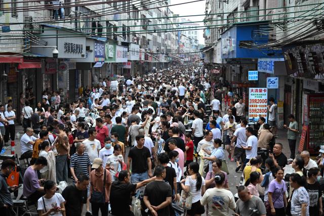This picture taken on April 27, 2026 shows job-seeking labourers and recruiters from clothing factories on a street in an urban village in Guangzhou, in southern China's Guangdong province. Vacuum cleaners and vapes could get more expensive if the Iran war drags on for much longer, Chinese factory owners and traders warn, as the world's manufacturing hub reels from "crazy" costs. (Photo by Pedro PARDO / AFP) / To go with 'CHINA-IRAN-MANUFACTURING-TRADE-PLASTIC,FOCUS' by Mary YANG and Tommy WANG