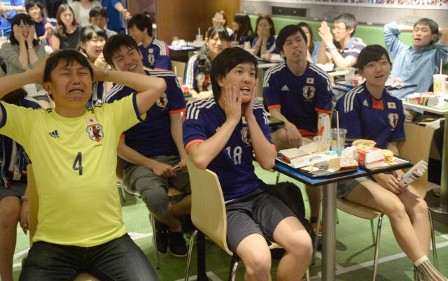 (FILES) Japanese football fans react after the second goal by Ivory Coast against Japan as they watch TV during the the group C first round match of the 2014 FIFA World Cup in Tokyo on June 15, 2014. Swathes of football-mad Asia from China to India, Malaysia and Thailand, are yet to announce broadcast rights for the biggest-ever World Cup with kick-off barely one month away. (Photo by TORU YAMANAKA / AFP)