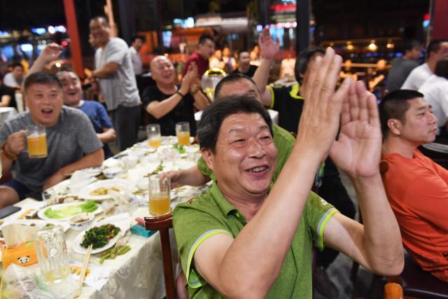 (FILES) This photo taken on July 2, 2018 shows football fans reacting while watching the 2018 Russia World Cup football match between Brazil and Mexico on a TV screen in a restaurant in Beijing. Swathes of football-mad Asia from China to India, Malaysia and Thailand, are yet to announce broadcast rights for the biggest-ever World Cup with kick-off barely one month away. (Photo by GREG BAKER / AFP)