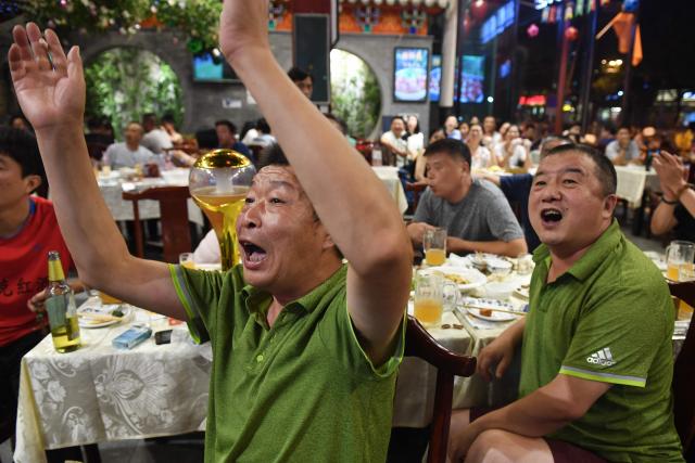 (FILES) This photo taken on July 2, 2018 shows football fans reacting while watching the 2018 Russia World Cup football match between Brazil and Mexico on a TV screen in a restaurant in Beijing. Swathes of football-mad Asia from China to India, Malaysia and Thailand, are yet to announce broadcast rights for the biggest-ever World Cup with kick-off barely one month away. (Photo by GREG BAKER / AFP)