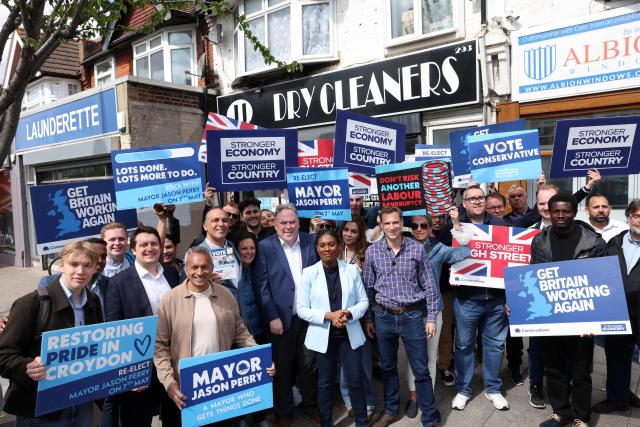 Britain's main opposition Conservative Party leader Kemi Badenoch (C) stands with Britain's main opposition Conservative Party Shadow Home Secretary Chris Philp (C right), and Conservative Cadidate for Mayor of Croydon, Jason Sperry (C Left), as she undertakes a "branded taxi tour" at various points across the capital, in Croydon, south London on May 6, 2026, visiting key areas a day before British local elections. British voters head to the polls on May 7 for local elections set to pile more misery on unpopular Labour Prime Minister Keir Starmer and cement the rise of right- and left-wing populists. (Photo by Adrian DENNIS / AFP)