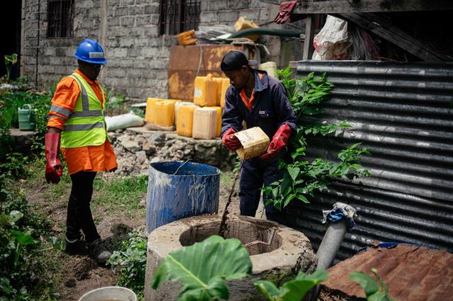 Victoire Materanya (L), co-founder of Umoja, watches as a worker mixes waste from a duck enclosure to put in the digester in order to produce clean energy in Goma on April 20, 2026. Most of the city's nearly one million people cannot afford to use electricity and mostly depend on charcoal, called makala, for cooking and heating.
Some people are switching to biogas, a renewable energy source that is cheaper and locally produced.
Biogas is produced by the decomposition of organic matter.
It has been made in Goma since 2016 by Umoja, a local company whose stated aim is to offer an alternative to firewood, which destroys forests. (Photo by Jospin Mwisha / AFP)