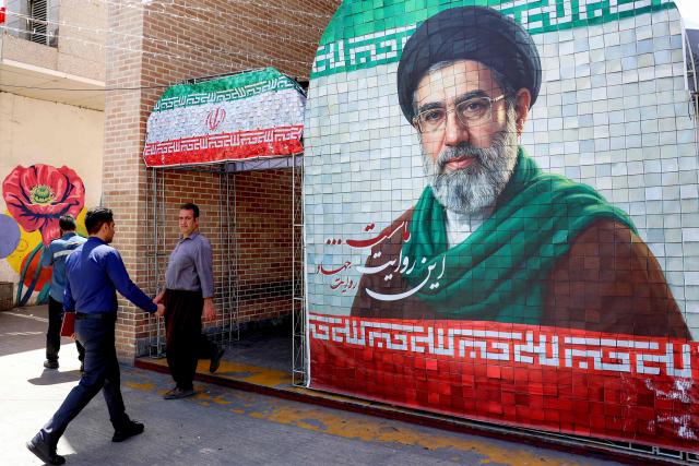 A man walks past a banner depicting Iran's current supreme leader Ayatollah Mojtaba Khamenei along a street Tehran on May 6, 2026. The United States and Pakistan, a key mediator in the Middle East war, expressed new hope of talks leading to a peace deal with Iran on May 6, after President Donald Trump halted a plan to guide ships through the Strait of Hormuz. (Photo by AFP) / 