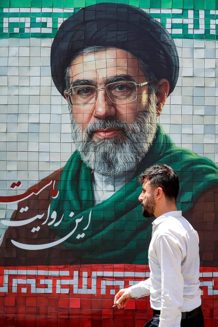 A man walks past a banner depicting Iran's current supreme leader Ayatollah Mojtaba Khamenei along a street Tehran on May 6, 2026. The United States and Pakistan, a key mediator in the Middle East war, expressed new hope of talks leading to a peace deal with Iran on May 6, after President Donald Trump halted a plan to guide ships through the Strait of Hormuz. (Photo by AFP) / 