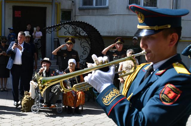World War Two veteran Aspek Dumashev, 102, receives congratulations from Kyrgyz servicemen as part of the Victory Day celebrations in Bishkek on May 6, 2026. Kyrgyzstan will celebrate the 81st anniversary of the Soviet Union's victory over Nazi Germany on May 9. (Photo by Vyacheslav OSELEDKO / AFP)