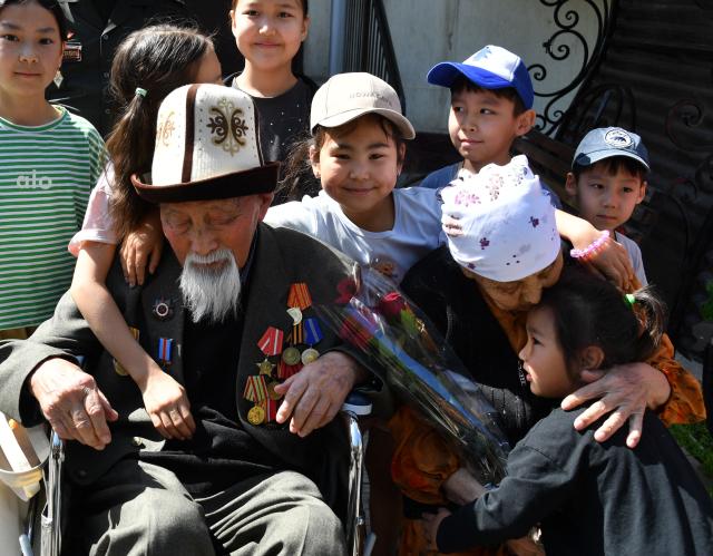 World War Two veteran Aspek Dumashev, 102, receives congratulations from Kyrgyz servicemen as part of the Victory Day celebrations in Bishkek on May 6, 2026. Kyrgyzstan will celebrate the 81st anniversary of the Soviet Union's victory over Nazi Germany on May 9. (Photo by Vyacheslav OSELEDKO / AFP)