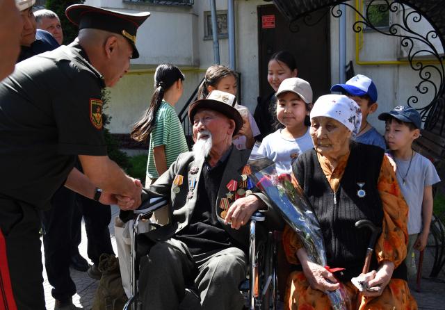 World War Two veteran Aspek Dumashev, 102, receives congratulations from Kyrgyz servicemen as part of the Victory Day celebrations in Bishkek on May 6, 2026. Kyrgyzstan will celebrate the 81st anniversary of the Soviet Union's victory over Nazi Germany on May 9. (Photo by Vyacheslav OSELEDKO / AFP)