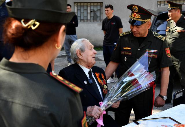 World War Two veteran Mikhail Sukhinin, 99, receives congratulations from Kyrgyz servicemen as part of the Victory Day celebrations in Bishkek on May 6, 2026. Kyrgyzstan will celebrate the 81st anniversary of the Soviet Union's victory over Nazi Germany on May 9. (Photo by Vyacheslav OSELEDKO / AFP)