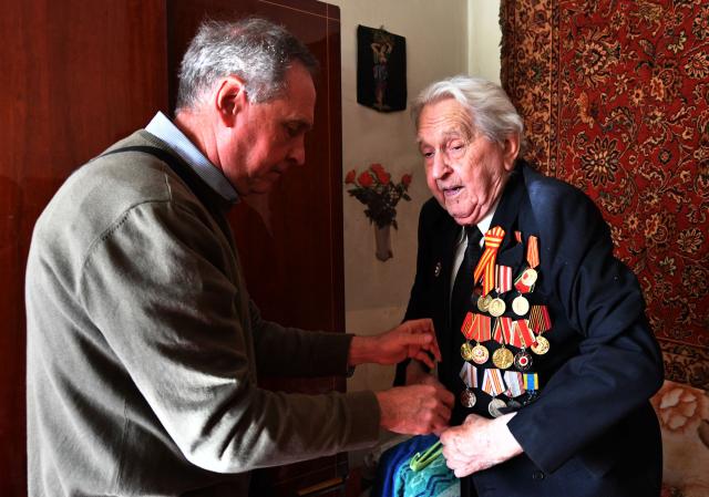 World War Two veteran Mikhail Sukhinin, 99, receives congratulations from Kyrgyz servicemen as part of the Victory Day celebrations in Bishkek on May 6, 2026. Kyrgyzstan will celebrate the 81st anniversary of the Soviet Union's victory over Nazi Germany on May 9. (Photo by Vyacheslav OSELEDKO / AFP)