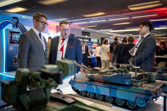 Participants stand in front of a mockup of the Korean-made K2 Black Panther tank during the "Defence24 Days" – a conference on defence and security attended by various leaders and experts from the region, in Warsaw, Poland, on May 6, 2026. (Photo by Wojtek RADWANSKI / AFP)