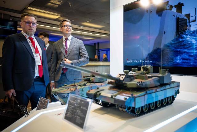 Participants stand in front of a mockup of the Korean-made K2 Black Panther tank (R) during the "Defence24 Days" – a conference on defence and security attended by various leaders and experts from the region, in Warsaw, Poland, on May 6, 2026. (Photo by Wojtek RADWANSKI / AFP)