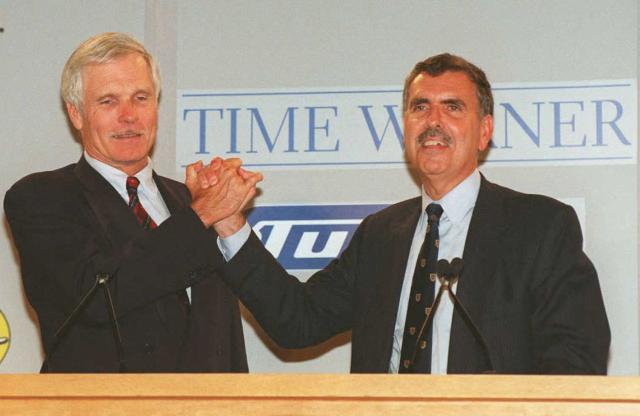 (FILES) Ted Turner (L) and Gerald Levin (R) shake hands during a news conference on September 22, 1995, in New York, to announce an agreement between Time Warner and Turner Broadcasting. Ted Turner, who transformed television news with the creation of CNN in 1980, has died at the age of 87, the network said on May 6, 2026. Cable News Network upended established broadcasting with its dedication to around-the-clock breaking news and shot to global recognition with its coverage of the Gulf War in 1990-91. (Photo by Don EMMERT / AFP)