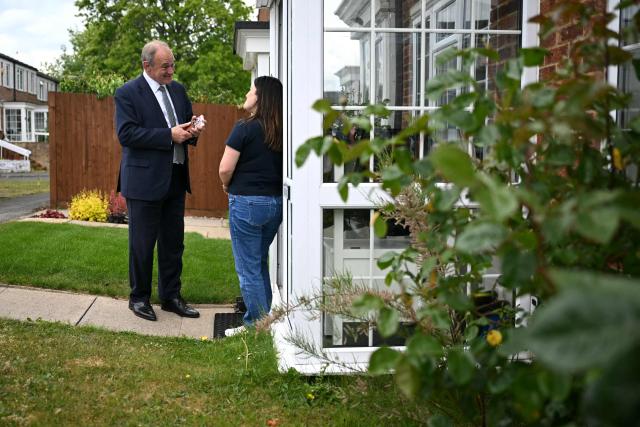 Britain's Liberal Democrat party leader Ed Davey speaks to a member of the public as the party canvases voters in Redhill, Surrey, south of London on May 6, 2026, a day before British local elections. British voters head to the polls on May 7 for local elections set to pile more misery on unpopular Labour Prime Minister Keir Starmer and cement the rise of right- and left-wing populists. (Photo by JUSTIN TALLIS / AFP)