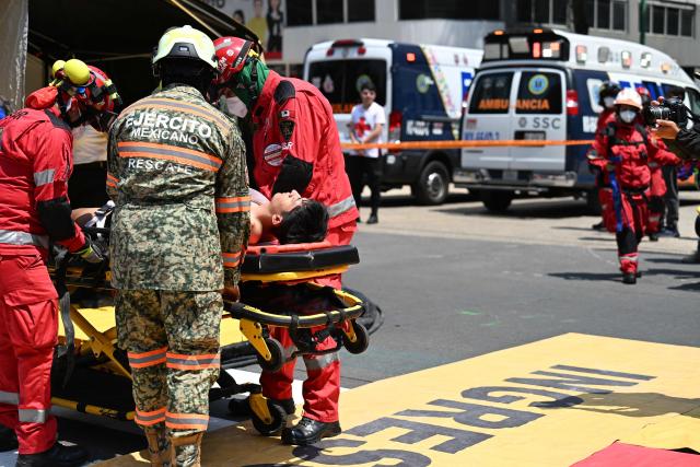 Rescue teams from the Mexican Army and the Red Cross assist simulated victims of a chemical-biological contaminant leak during an earthquake drill in Mexico City on May 6, 2026. (Photo by Yuri CORTEZ / AFP)