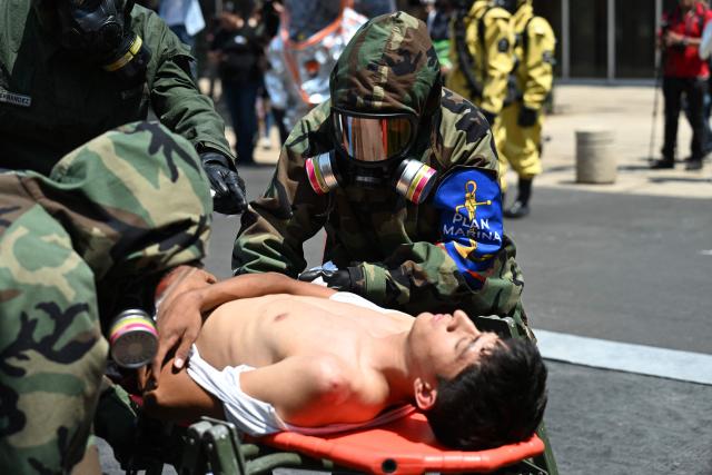 Rescue teams from the Mexican Army assist simulated victims of a chemical-biological contaminant leak during an earthquake drill in Mexico City on May 6, 2026. (Photo by Yuri CORTEZ / AFP)