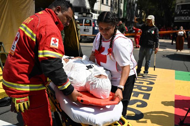 Rescue teams of the Mexican Red Cross evacuate a simulated victim from a supposedly collapsed building at the Plaza del Monumento a la Revolucion during an earthquake drill in Mexico City on May 6, 2026. (Photo by Yuri CORTEZ / AFP)