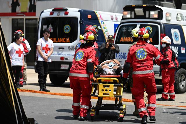A Mexican Red Cross rescue team evacuates a simulated victim from a supposedly collapsed building at the Monument to the Revolution Plaza during an earthquake drill in Mexico City on May 6, 2026. (Photo by Yuri CORTEZ / AFP)