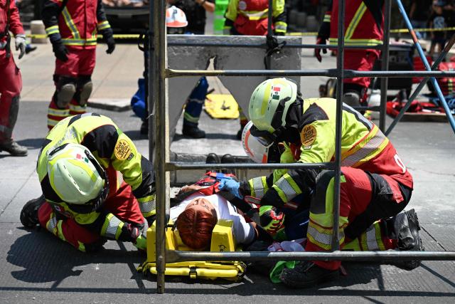 A Mexican Red Cross rescue team assists a simulated victim from a supposedly collapsed building at the Monument to the Revolution square during an earthquake drill in Mexico City on May 6, 2026. (Photo by Yuri CORTEZ / AFP)