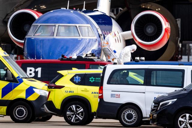 This photograph shows a person in a white hazmat suit (Centre R) disembarking a Bombardier Challenger 605 medical aircraft allegedly carrying some of the passengers believed to be infected with hantavirus from the cruise ship MV Hondius, before being escorted to an ambulance at Schiphol Airport in Amsterdam on May 6, 2026. A plane that left Cape Verde following the evacuation of a cruise ship hit by the hantavirus landed in Spain's Canary Islands on May 6, while a second flight headed for the Netherlands. (Photo by Jeffrey Groeneweg / ANP / AFP) / Netherlands OUT