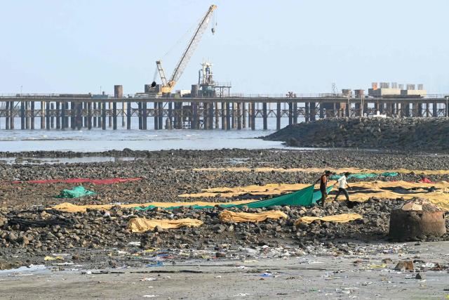Workers arrange tent cloth for drying on the rocky shores along the under-construction Sea Link coastal road project in Mumbai on May 8, 2026. (Photo by Indranil Mukherjee / AFP)