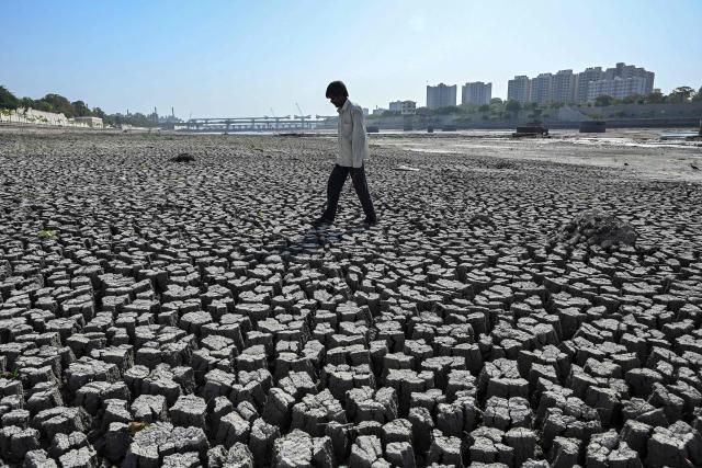 A man walks on the dry riverbed of the Sabarmati River in Ahmedabad on May 8, 2026. (Photo by Shammi MEHRA / AFP)