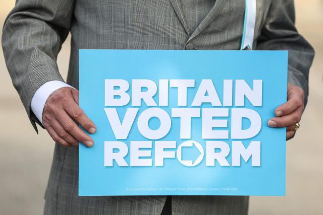 A member of the Reform UK party holds a placard as he waits for the arrival of Reform UK leader Nigel Farage outside the Havering Town Hall a day after local elections in east London on May 8, 2026. (Photo by Toby Shepheard / AFP)