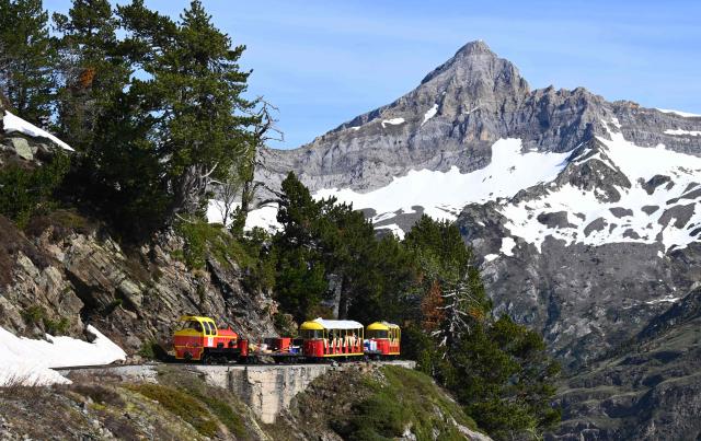 This photograph shows a view of the little train of Artouste, a historic tourist railway,  passing on the mountainside ahead of its opening to the public on May 8th in Artouste near Laruns, south-western France, on May 7, 2026. The Artouste little train is located in the Ossau Valley, in the Pyrenees-Atlantiques department of France. This historic tourist railway offers a mountain excursion at an altitude of over 2,000 meters. It travels 10 kilometers on its narrow-gauge track. It is the highest narrow-gauge railway in Europe. (Photo by Gaizka IROZ / AFP)