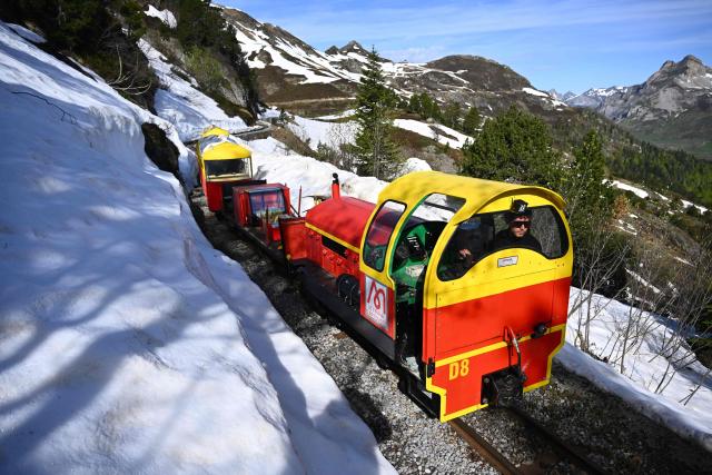 This photograph shows a view of the little train of Artouste, a historic tourist railway,  passing between snow ahead of its opening to the public on May 8th in Artouste near Laruns, south-western France, on May 7, 2026. The Artouste little train is located in the Ossau Valley, in the Pyrenees-Atlantiques department of France. This historic tourist railway offers a mountain excursion at an altitude of over 2,000 meters. It travels 10 kilometers on its narrow-gauge track. It is the highest narrow-gauge railway in Europe. (Photo by Gaizka IROZ / AFP)