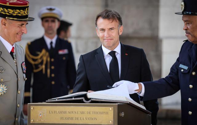 France's President Emmanuel Macron signs the guest book at the Arc de Triomphe during a ceremony marking the 81st anniversary of Victory in Europe Day, which commemorates the end of the Second World War in Europe, in Paris on May 8, 2026. (Photo by Ludovic MARIN / POOL / AFP)
