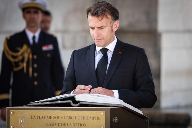 France's President Emmanuel Macron signs the guest book at the Arc de Triomphe during a ceremony marking the 81st anniversary of Victory in Europe Day, which commemorates the end of the Second World War in Europe, in Paris on May 8, 2026. (Photo by Ludovic MARIN / POOL / AFP)