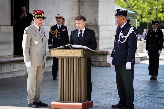 France's President Emmanuel Macron signs the guest book at the Arc de Triomphe during a ceremony marking the 81st anniversary of Victory in Europe Day, which commemorates the end of the Second World War in Europe, in Paris on May 8, 2026. (Photo by Ludovic MARIN / POOL / AFP)