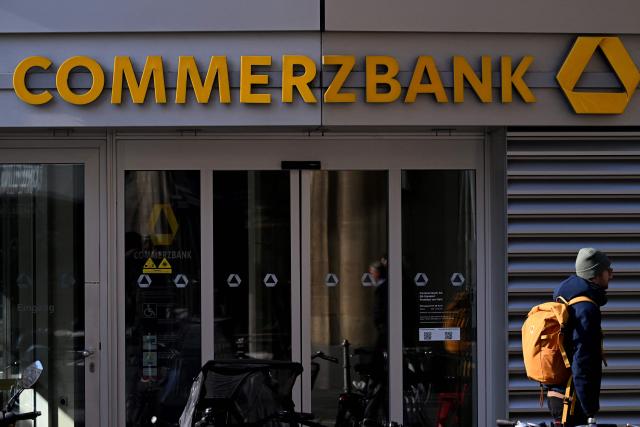(FILES) A pedestrian walks past the Commerzbank building with the bank's logo in the banking district skyline in Frankfurt am Main, western Germany, on November 6, 2025. Germany's Commerzbank will cut up to 3,000 jobs as it battles to fend off a hostile takeover bid from Italy's UniCredit, the German firm said on May 8, 2026. (Photo by Kirill KUDRYAVTSEV / AFP)