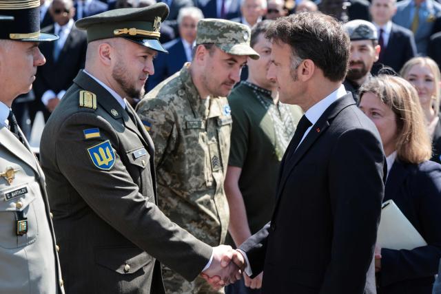 France's President Emmanuel Macron (R) shakes hands with Ukrainian servicemen invited to attend the ceremony marking the 81st anniversary of Victory in Europe Day, which commemorates the end of the Second World War in Europe,  at the Arc de Triomphe in Paris on May 8, 2026. (Photo by Ludovic MARIN / POOL / AFP)