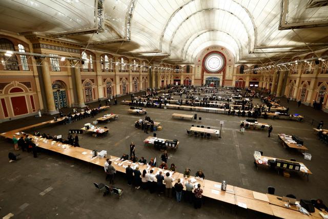 Staff count votes on ballot papers the morning after local elections, at a vote-counting centre inside Alexandra Palace, north London on May 8, 2026. Nigel Farage, leader of the Britain's hard-right nationalist Reform UK party, vowed Friday it was "here to stay" after winning hundreds of seats in local polls. (Photo by Brook Mitchell / AFP)