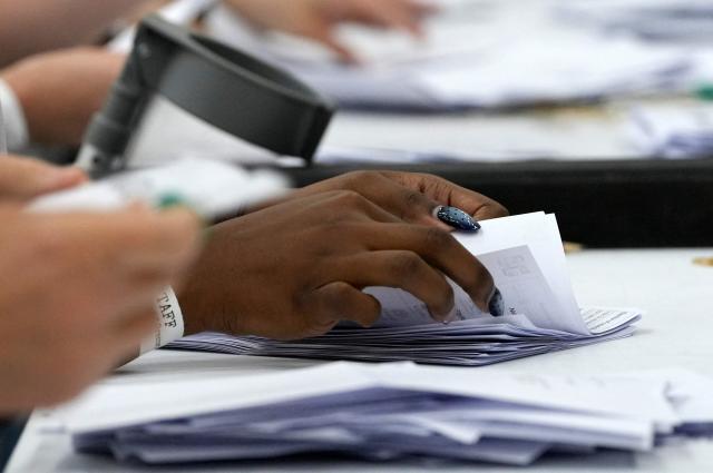 Staff count ballots the morning after local elections at a vote-counting centre in Woolwich in south-east London on May 8, 2026. Nigel Farage, leader of the Britain's hard-right nationalist Reform UK party, vowed Friday it was "here to stay" after winning hundreds of seats in local polls. (Photo by CARLOS JASSO / AFP)