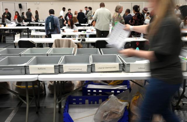 Staff count ballots the morning after local elections at a vote-counting centre in Woolwich in south-east London on May 8, 2026. Nigel Farage, leader of the Britain's hard-right nationalist Reform UK party, vowed Friday it was "here to stay" after winning hundreds of seats in local polls. (Photo by CARLOS JASSO / AFP)