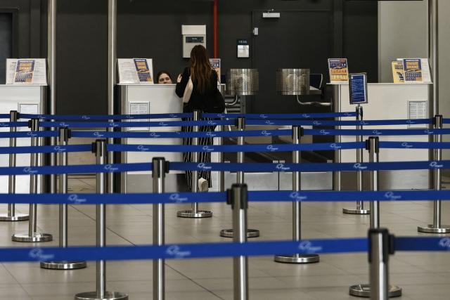 (FILES) A passenger stands at the check-in counter in the Thessaloniki airport "Makedonia" in Thessaloniki on May 7, 2026. Airlines must not charge customers extra fuel fees after they have already bought tickets, the EU warned on May 8, 2026, as the aviation sector feels the pain from high energy prices because of the Middle East war. (Photo by Sakis Mitrolidis / AFP)