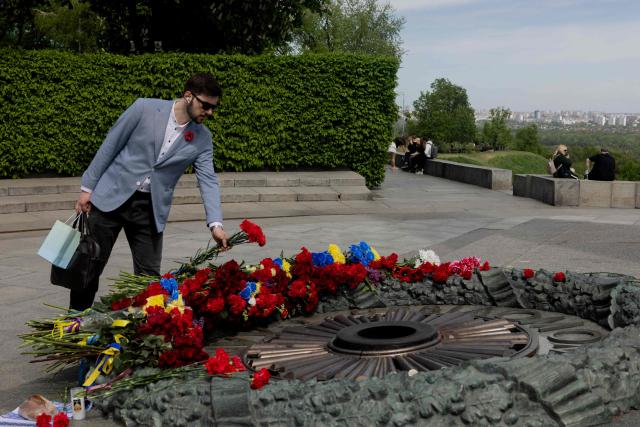 A man lays a flower bouquet on the Tomb of the Unknown Soldier at the WWII memorial on the 81st anniversary of VE Day, or Victory in Europe Day, or Day of Remembrance, which commemorates the end of World War II, in Kyiv, on May 8, 2026, amid the Russian invasion of Ukraine. (Photo by Tetiana DZHAFAROVA / AFP)