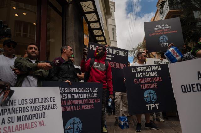 Dockers hold banners reading 'Workers of Tenerife port - TPT (Trabajadores del Puerto de Tenerife) - Port without means, Port unsafe' as they protest against the arrival of a cruise ship affected by hantavirus in Santa Cruz de Tenerife on May 8, 2026. Passengers aboard the MV Hondius cruise ship affected by a deadly hantavirus outbreak will start being flown to their countries of origin after the vessel arrives on the Canary island of Tenerife on May 10, 2026, the Spanish government said. (Photo by JORGE GUERRERO / AFP)