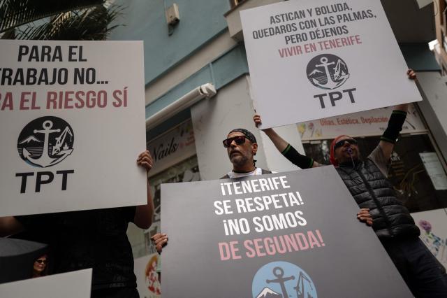 Dockers hold banners reading 'Workers of Tenerife port - TPT (Trabajadores del Puerto de Tenerife) - Respect Tenerife - we are not second-class' as they protest against the arrival of a cruise ship affected by hantavirus in Santa Cruz de Tenerife on May 8, 2026. Passengers aboard the MV Hondius cruise ship affected by a deadly hantavirus outbreak will start being flown to their countries of origin after the vessel arrives on the Canary island of Tenerife on May 10, 2026, the Spanish government said. (Photo by JORGE GUERRERO / AFP)