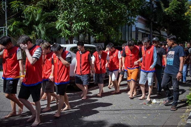 Indonesian police escort a group of suspects from China, Japan, and Taiwan before authorities held a press conference on an online fraud case in Surabaya on May 8, 2026. Dozens of Chinese, Japanese, and Taiwanese nationals have been arrested in Indonesia in connection with an online fraud case that has cost victims millions of dollars. (Photo by JUNI KRISWANTO / AFP)