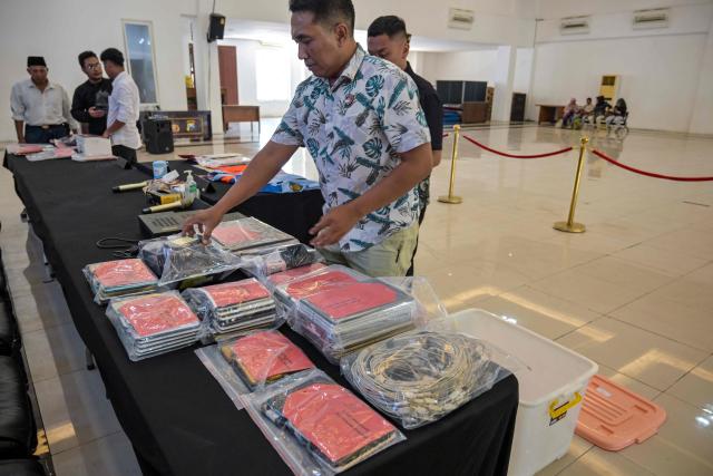 Indonesian police display evidence before authorities hold a press conference following the arrest of dozens of suspects in an online fraud case in Surabaya on May 8, 2026. Dozens of Chinese, Japanese, and Taiwanese nationals have been arrested in Indonesia in connection with an online fraud case that has cost victims millions of dollars. (Photo by JUNI KRISWANTO / AFP)