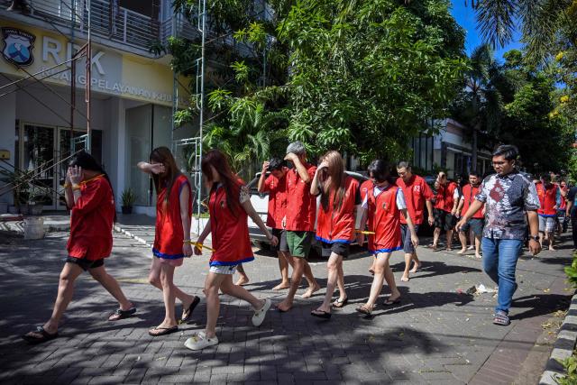 Indonesian police escort a group of suspects from China, Japan, and Taiwan before authorities held a press conference on an online fraud case in Surabaya on May 8, 2026. Dozens of Chinese, Japanese, and Taiwanese nationals have been arrested in Indonesia in connection with an online fraud case that has cost victims millions of dollars. (Photo by JUNI KRISWANTO / AFP)