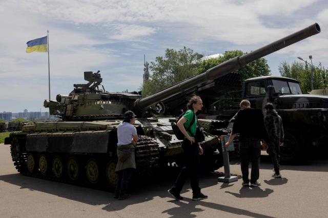 Teenagers walk past Soviet military equipment at a street exhibition near the National Museum of the History of Ukraine in the Second World War on the Day of Remembrance and Victory over Nazism in World War II, in Kyiv, on May 8, 2026, amid the Russian invasion of Ukraine. (Photo by Tetiana DZHAFAROVA / AFP)