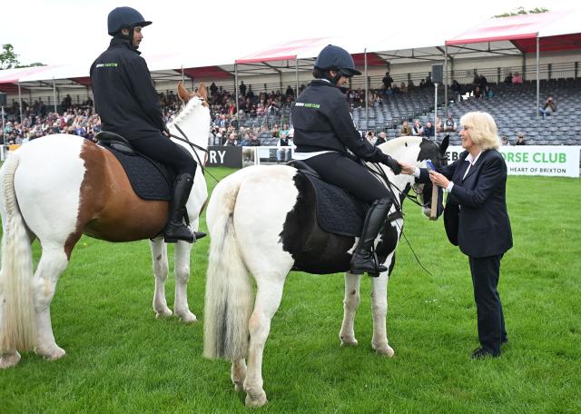 Britain's Queen Camilla smiles as she gives a rider a rosette at the Badminton Horse Trials in Badminton, central England on May 8, 2026. (Photo by Eddie Mulholland / POOL / AFP)