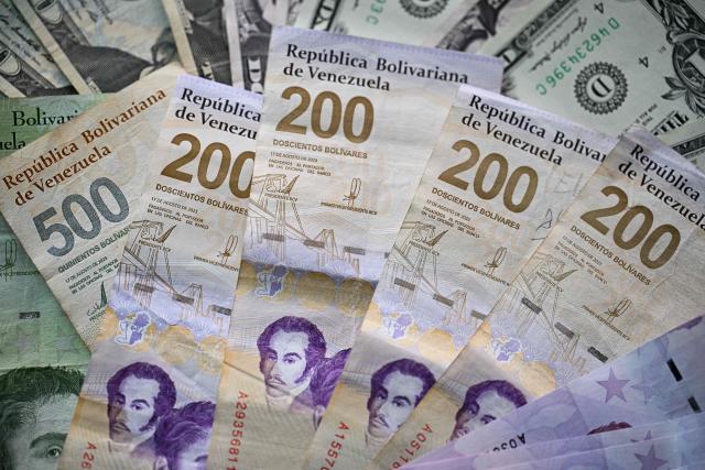 (FILES) Picture of Venezuelan bolivar and US dollar bills taken in Caracas on September 30, 2025. Formal dollarisation is a recurring fantasy in Venezuela that is gaining momentum in the absence of NicolAs Maduro. Adopting the US dollar is tempting in this country with extremely high inflation, but economists believe the move would be drastic, even under the supervision of the currency’s issuer. (Photo by Federico PARRA / AFP)